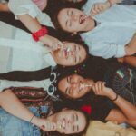 Joyful group of diverse women enjoying a sunny picnic with lollipops, showcasing friendship and fun.